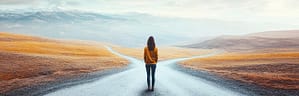 Person standing at a fork in the road, contemplating the path ahead.